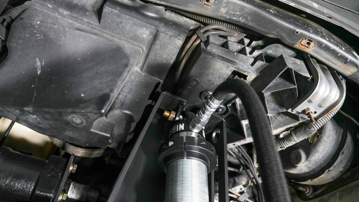 Motobilt Front Coilover Mounts MB1553 for Jeep JK / JKU view shows bilstein 2.5" coil over mounted and stock plastic inner fender support structure