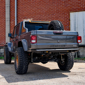 Back view of a lifted truck with with Motobilt Tomahawk high clearence bumper in front of a brick building.